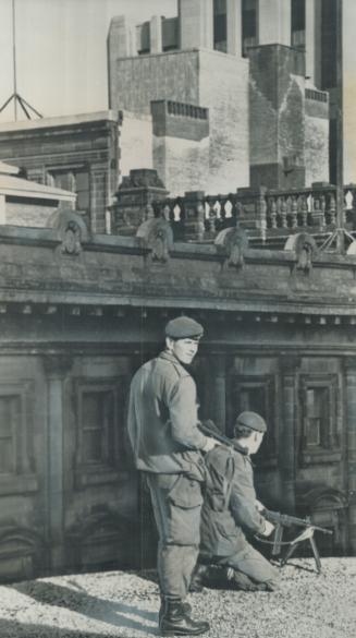 Training a Machine-Gun on the crowds below, soldiers stand guard on a rooftop while dignitaries arrive at Notre Dame Church for the funeral of murdere(...)
