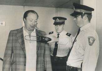 Scarborough, passes the search with flying colors as Constable Ken Pollitt of Mississauga police passes detector over him