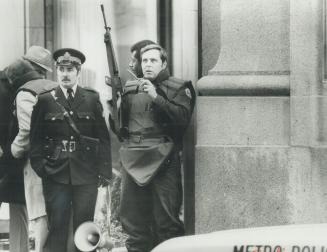 Police sharpshooter speaks into two-way radio as he watches bank at Yonge and King Sts