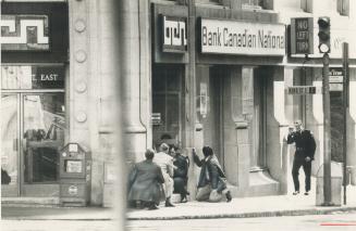 Policemen crouch at door of King and Yonge Sts
