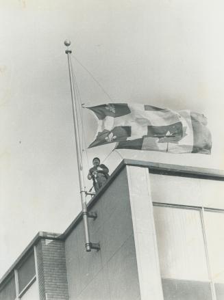 The flags come down as a security guard in Montreal, atop a public building, lowers both Canadian and Quebec provincial flags to half-staff in mourning for Quebec Labor Minister Pierre Laporte