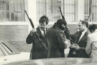 Two police officers examine shotguns after a holdup attempt