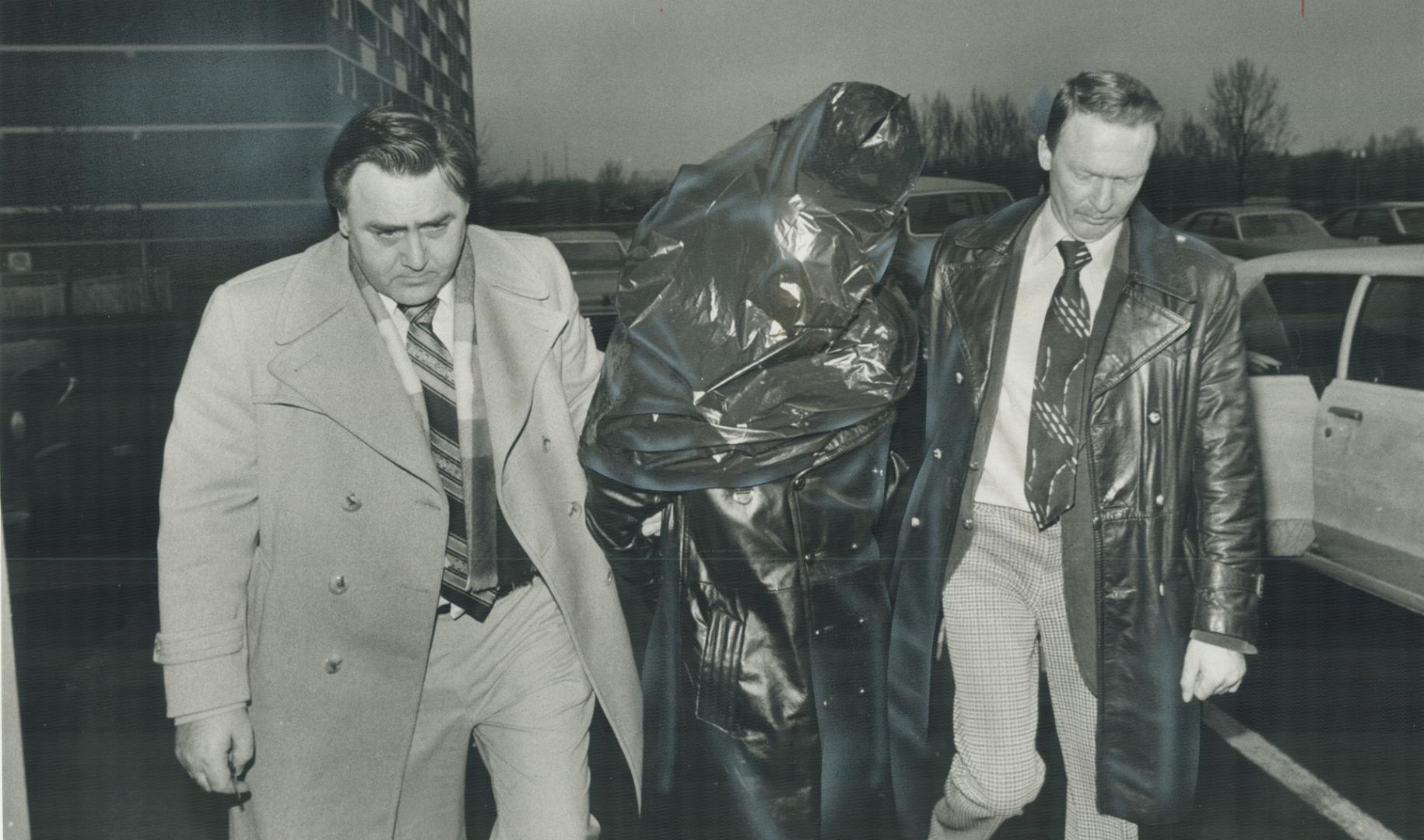 Faces maksed by garbage bags, three suspects in the pistol-whipping, $148,716 robbery of Canada Trust in Scarborough arrive at 41 division police station to take part in a line-up