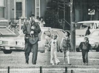 Small children trot beside a Metro policeman looking in Regent Park for two men seen entering an apartment in which a man was found shot in the chest.(...)