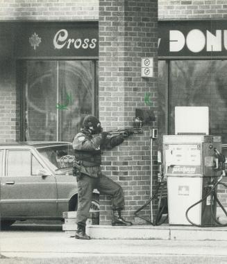 Gas attack: Wearing a mask to protect himself from fumes, a policeman prepares to fire a tear gas shell into a Scarborough variety store today