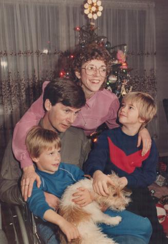 Family Christmas: Nepean police Constable Robin Easey, his wife Glennis, and sons, christopher, 5, left and Mathew, 7, cuddle family dog Shamrock in their home near Ottawa