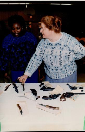 Tools of trade: At an Elm Bank Community Centre press conference, Jennifer Phillips, left, and Bonnie Killam look at some of the knives and guns seized in drug sweep