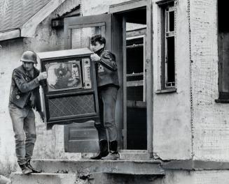 Cleaning up after the raid two members of Satan's Choice Club carry out their smashed TV set