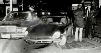 Aftermath of attack: Police check out a car in which a woman who had been attacked got free of her assailant by grabbing the wheel and forcing it into a parked car