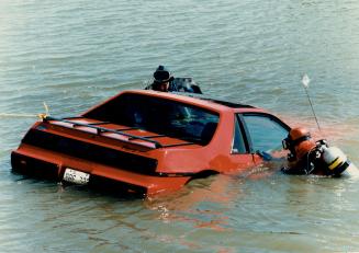 Theft aftermath: Peel police divers John Gordon and Mark Cripps inspect a Pontiac Fiero that was ditched in Lake Aquitaine in Mississauga after it was stolen