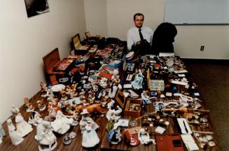 Recovered goods: Detectives Sergeant Don Mantle surveys jewelry and other valuables yesterday that police believe were stolen while their owners were attending funerals