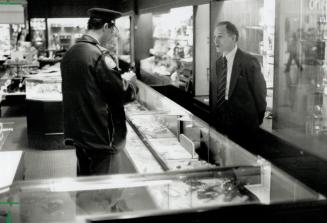 Image shows an interior of Birks store where an officer is questioning an employee.