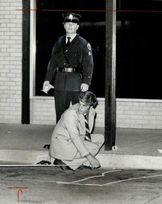 Constable Rene Brakel kneels beside dummy gun in front of store