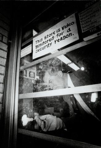 Clue search, A police officer dusts the door of a Scarborough variety store for fingerprints after a clerk was stabbed during a robbery attempt last night
