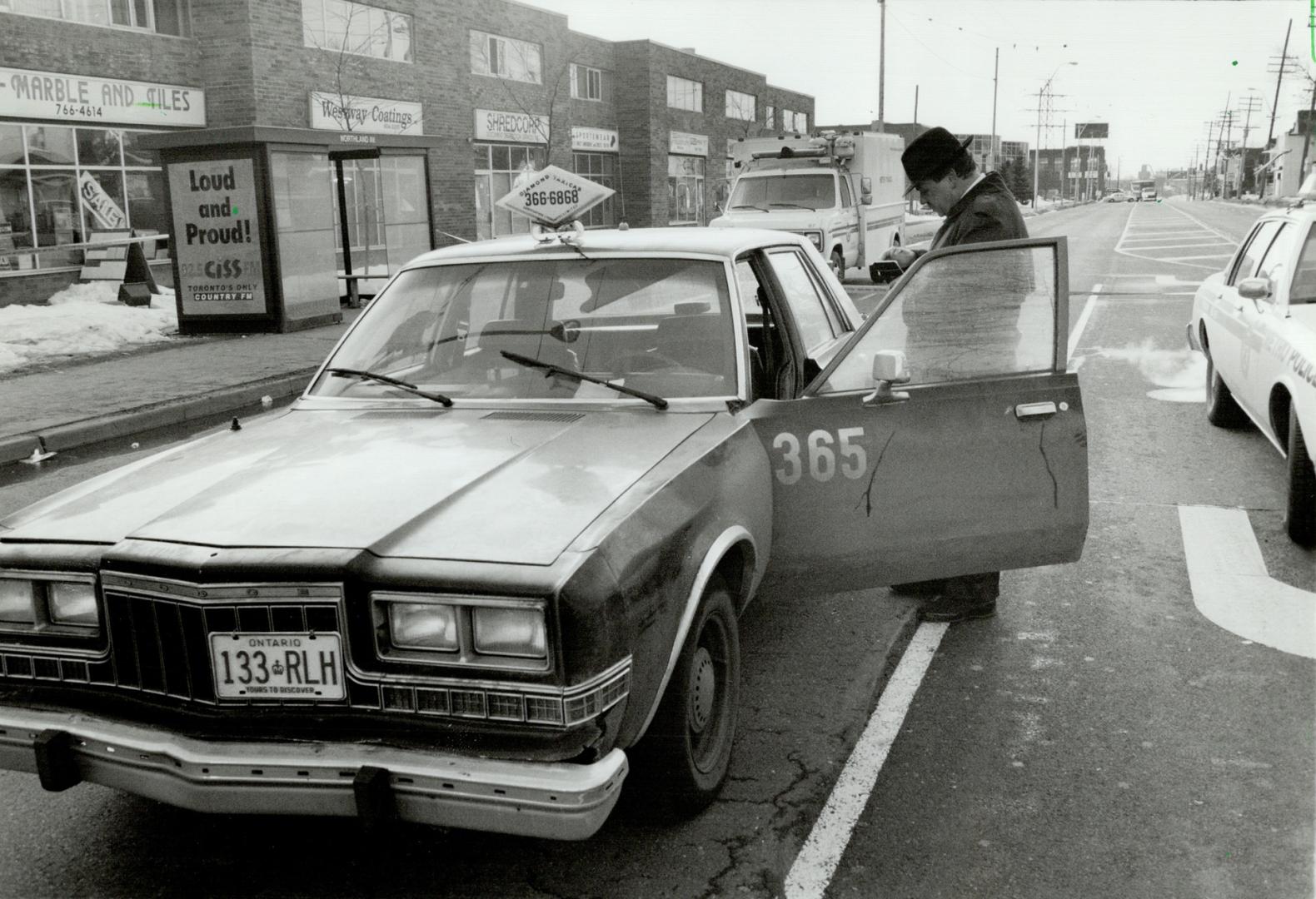 Bloody cab: Metro police check the cab in which they found its stabbed driver Ahmad Gondal yesterday on Weston Rd