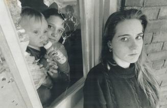 Close call. Denise Jones, 19, and her 15-month-old son, Brian, at left, and tenant Corry Doyle. 16, show how their livingroom window was blown out by (...)