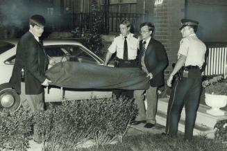 The bodies: Undertakers carry out a body, wrapped in a red blanket, to hearse