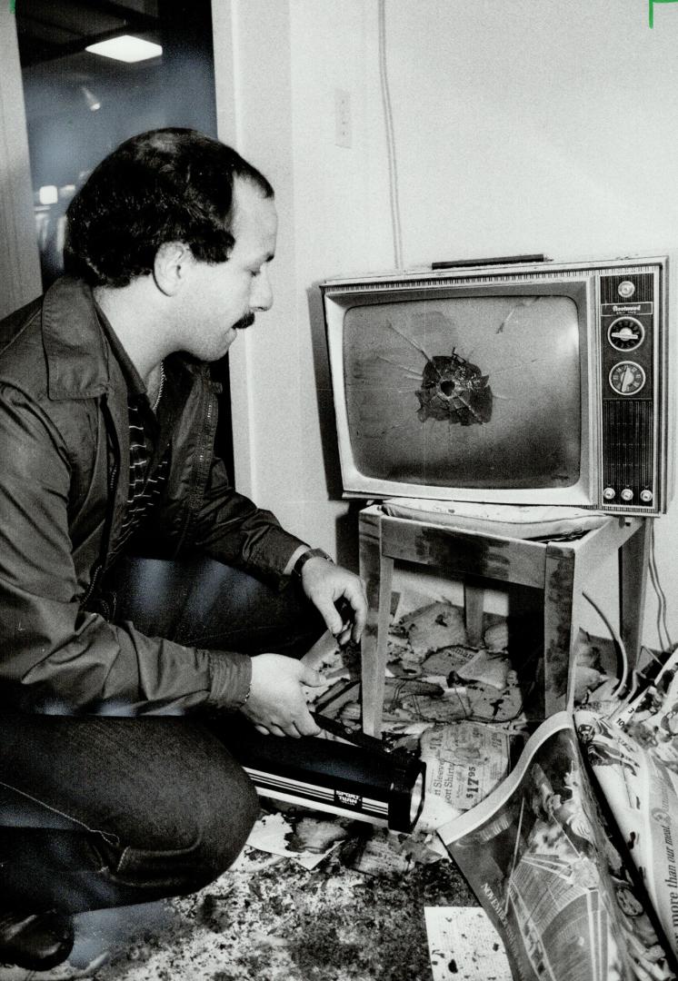 Random bullet: Steve Kozinets, manager of the Ontario store where an OPP constable was shot dead, examines a shattered television set, hit in the middle of the screen by a bullet