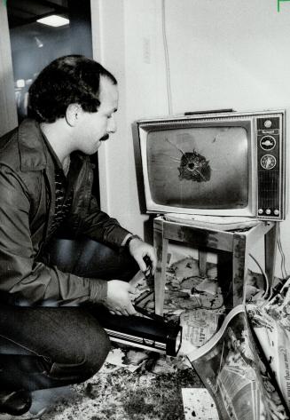 Random bullet: Steve Kozinets, manager of the Ontario store where an OPP constable was shot dead, examines a shattered television set, hit in the middle of the screen by a bullet