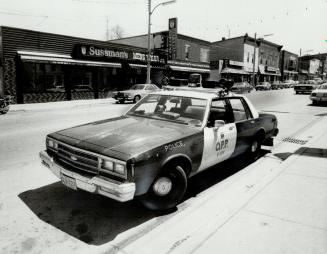 Waiting cruiser: His car sits across the street from Sussman's Mens Wear, at which he and his partner were answering a fire call, but Constable Rick Hopkins, 31, won't be coming back to it