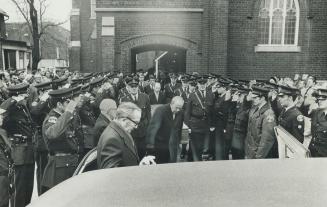 Flanked by double rows of saluting police, sealed oak coffin containing the body of Constable James Lothian is carried out of Hope United Church today(...)