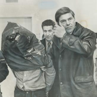 Convicted killer Rene Vaillancourt in a 1973 mug shot, left, and being led into court with his head covered, above