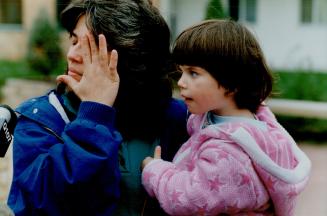 A Mother's Tears: Lisa Young, a tenant in the building where a child's body was found yesterday, weeps as she holds her daughter, Amy