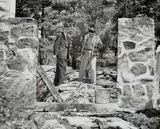 Inspecting ruins of honeymoon cottage from which he pulled his friend, Jack Kettlewell, before it burned, Ronald Barrie, right is seen with Insp. Thomas Wright