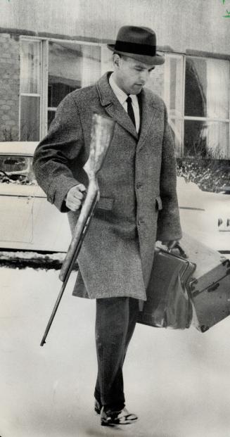 Suspected death weapon-a .22 rifle-is carried by Det. Roy Gosby during investigation into the slaying Sunday of 11-year-old Dieter Strodthoff in Scarb(...)