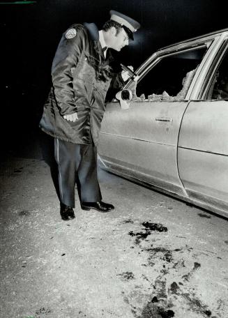 Suicide car: Constable Ted Doyle examines car driven by George Mitskopolous, 26, who blew out the door window when he shot himself fatally in the head