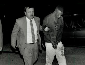 Slaying Suspect: Police detective Gerald Ball Escorts Philip Anthony Clarke, 19, of Toronto last night after Clarke was charged with first-degree murder
