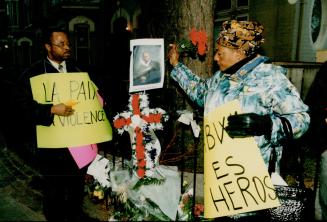 Mbutu Missinga, left, and Maman Tumba hold up a photo of Freddas Jim Bwabwa at last night's vigil