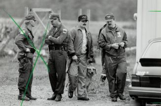 Clues sought: Brad Bennett, left, of the sheriff's office in Rochester and Halton Constable Paul Delaney use a special dog yesterday to search a farm