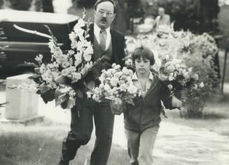 Helping hands: Eight-year-old Shawn Paul Manone helps a funeral director carry flowers to the graveside