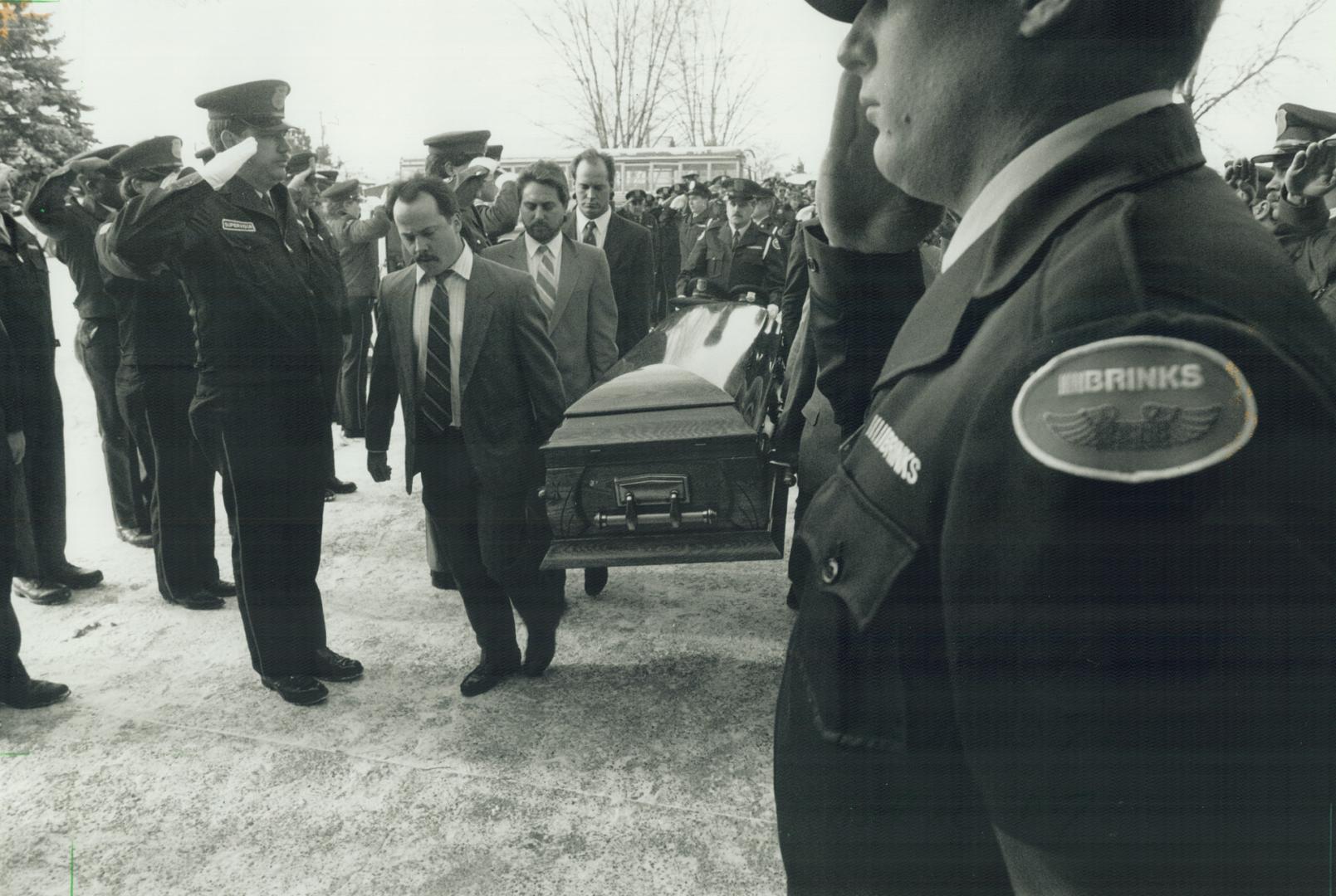 Honoring a colleague: Brinks guards salute as a casket containing the body of their slain colleague, Malcolm (Rick) Bridgman, 31, is carried into Whitby's Free Methodist Church yesterday