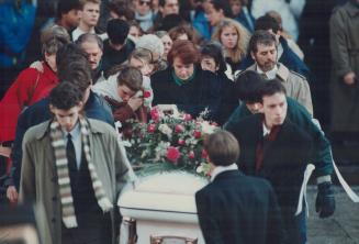 Sad procession: Grieving mourners crowd around as engineering students carry a casket of a colleague from Notre Dame Basilica after a funeral Mass yesterday for massacre victims