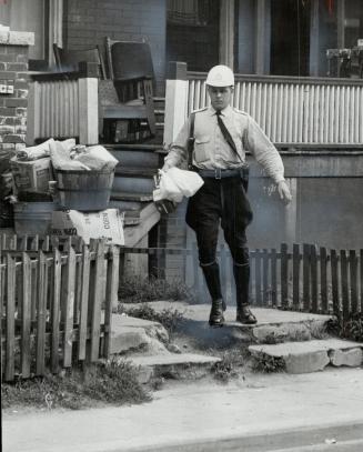 Police Officer carries bags and empty pop bottles from rear of 100 Granby St