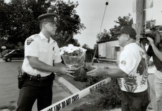 Officer at the scene accepts flowers from a resident