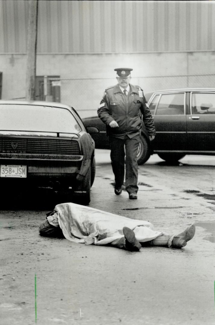 Slaying victim: The body of Joginder Singh Brar lies on the pavement of a Misissauga industrial mall yesterday where he once owned an auto repair business