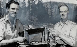 Pat Adams, left, a game warden, and Fred Kirouac hold a box containing a bone and blood-splattered bits of clothing