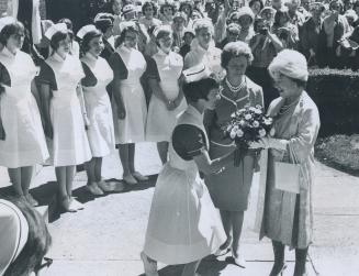 Hospital visit: Vivien Jacobs, president of the Student Nurse Council at women's College hospital, presents a bouquet to the Queen Mother, while Dorothy Machan, hospital administrator, looks on