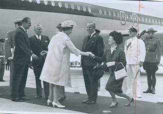 Mrs. Lester Pearson curtseys to Queen Elizabeth at Uplands Airport, Ottawa, and Canada's birthday celebrations are officially under way. Others greeti(...)