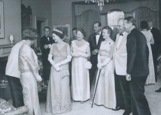 Prime Minister Pearson, his white jacket just visible on the far left, takes time out for a joke before dinner which brings smile from the Queen. Mrs.(...)
