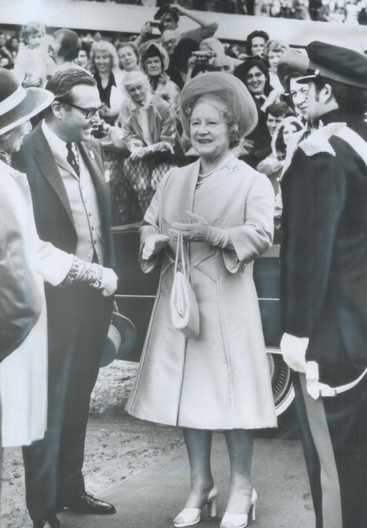 Smiling happly despite the mud and the wet weather, the Queen Mother talks with Lt