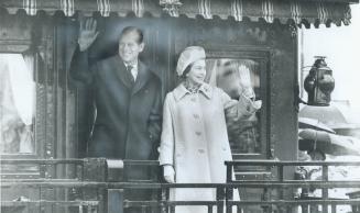 The Queen and Prince Philip wave from royal train carriage