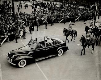 With mounted soldiers in full-dress uniform accompanying the royal car, the King and Queen swing out from the Calgary station after the brief receptio(...)