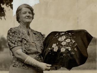 Sending own workmanship to Queen, Mrs. John German of St. George, Ont., is sending the Queen this beautiful black satin cushion top decorated with Canadian wild roses which she painted herself