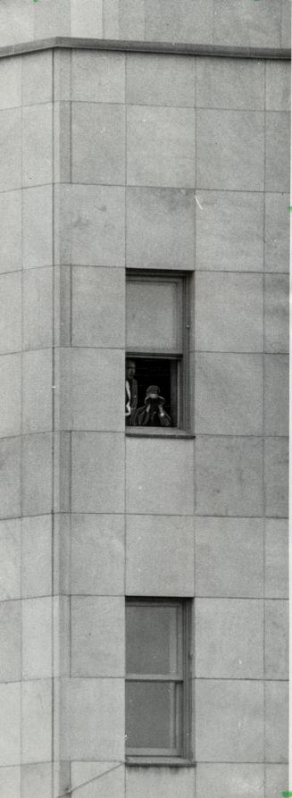 Alert Gpards, one with binoculars, man a security post at a window in the Confederation hall and keep a close eye on the crowd below and nearby buildings