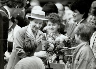 Queen accepting flowers from kids during her walkabout in downtown Vancouver followed by Mayor Gordon Campbell