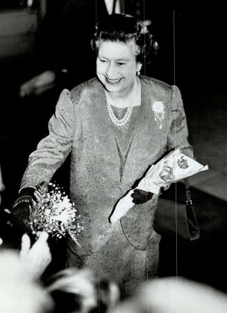 Queen accepting flowers from bystanders before entering hotel Vanc